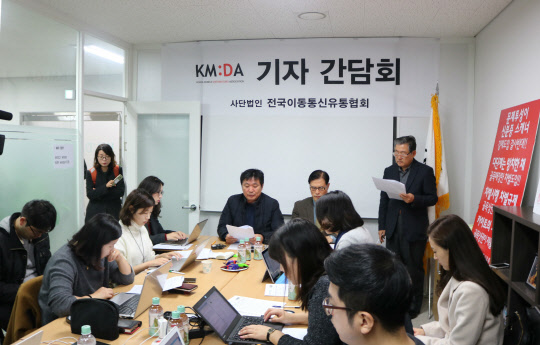 전국이동통신유통협회는 5일 기자간담회를 열고 지난 1일부터 의무화된 신분증 스캐너 도입에 대해 법적 근거가 없을 뿐만 아니라, 유통점을 상대로 하는 수익사업으로 변질되고 있다고 주장했다. 이날 협회 부회장(뒷줄 맨왼쪽), 김신구 협회 상근부회장(가운데) 등이 신분증 스캐너의 문제점을 설명하고 있다.  전국이동통신유통협회 제공